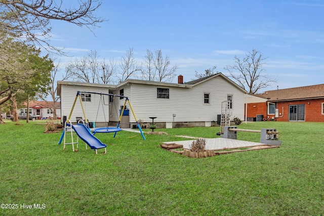 back of property featuring central AC, a yard, and a playground