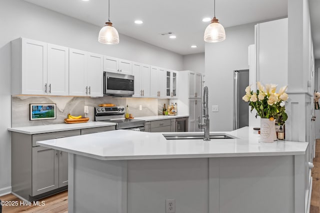 kitchen with stainless steel appliances, gray cabinets, pendant lighting, and kitchen peninsula