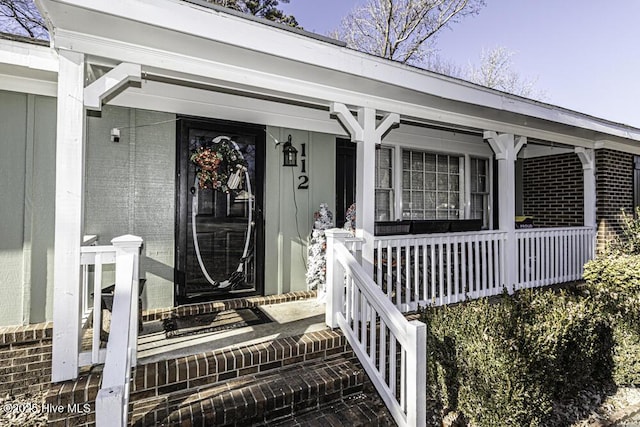 entrance to property featuring brick siding and a porch