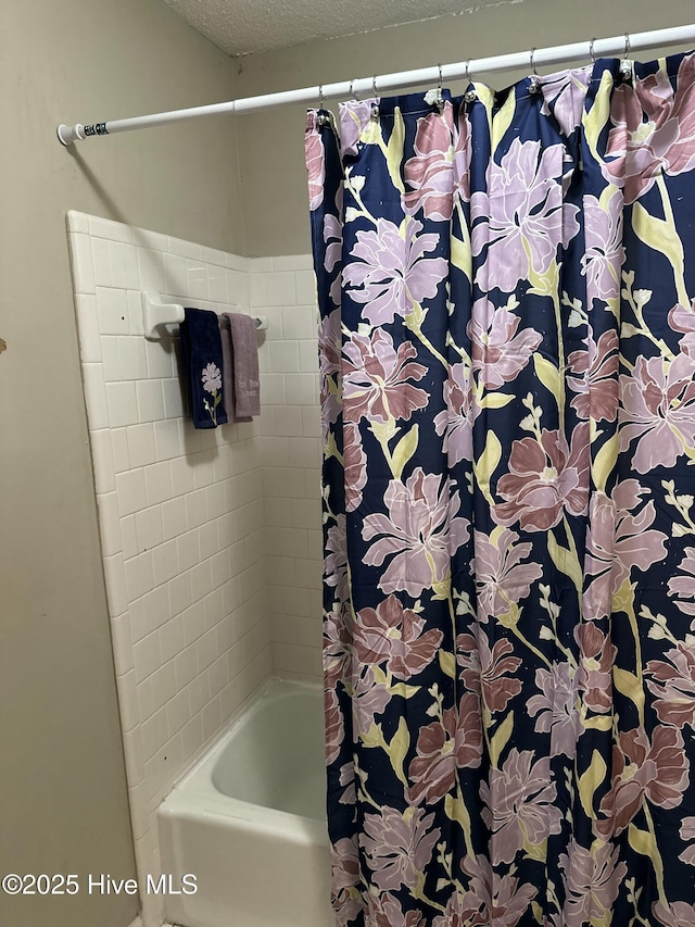 full bath with a textured ceiling and shower / tub combo with curtain