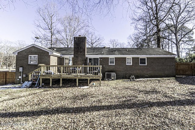 rear view of property with brick siding, fence, cooling unit, a chimney, and a deck