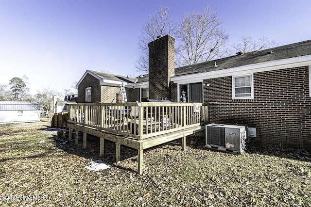 back of property featuring brick siding, central AC, a deck, and a chimney