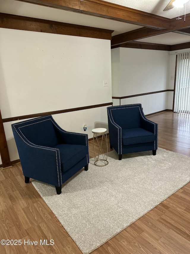 living area with beamed ceiling, wood finished floors, and ceiling fan