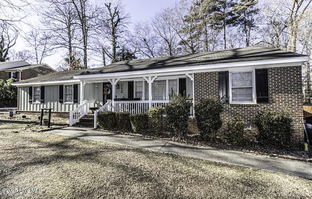 view of front of property with board and batten siding, covered porch, and brick siding