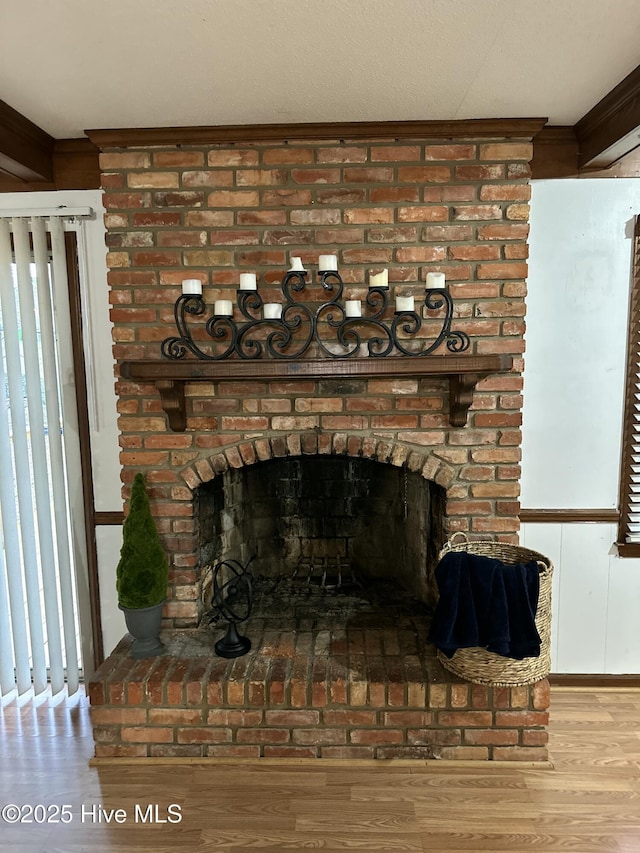 room details featuring a brick fireplace, wood finished floors, and crown molding