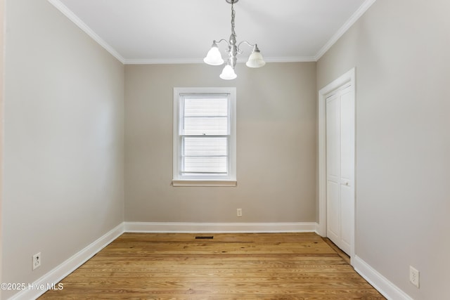 spare room with light wood-type flooring, baseboards, an inviting chandelier, and ornamental molding