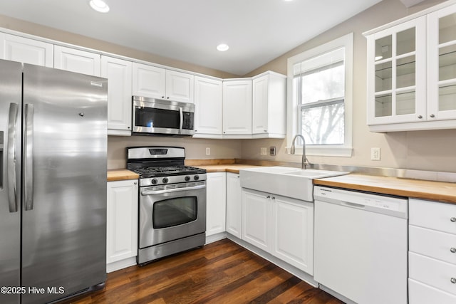 kitchen featuring glass insert cabinets, white cabinetry, a sink, wood counters, and appliances with stainless steel finishes