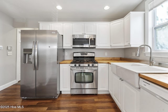 kitchen featuring wood counters, dark wood finished floors, appliances with stainless steel finishes, and a sink