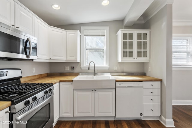 kitchen with butcher block countertops, white cabinetry, appliances with stainless steel finishes, and a sink