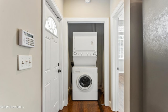 laundry area featuring dark wood finished floors, baseboards, and stacked washer and dryer