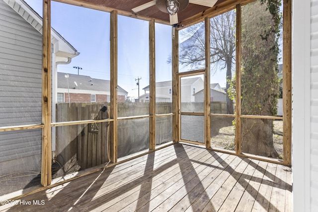 unfurnished sunroom with a residential view and ceiling fan