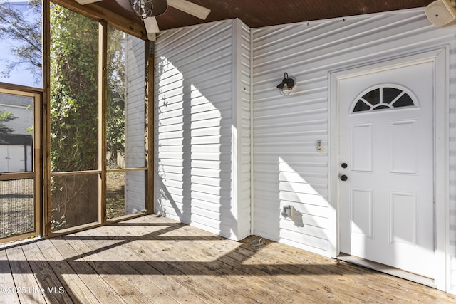 entrance to property with ceiling fan and a deck