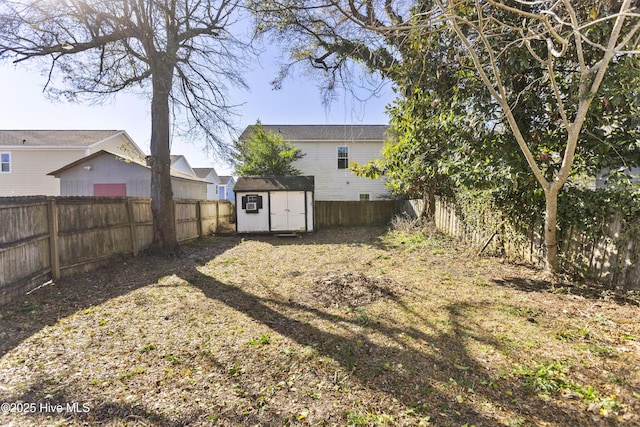 view of yard with a storage shed, an outbuilding, and a fenced backyard