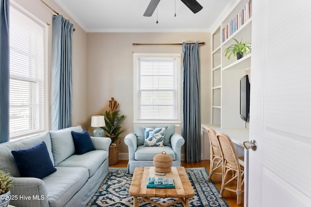 living area with ceiling fan, ornamental molding, and wood finished floors