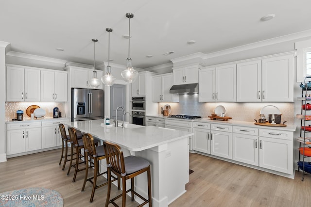 kitchen featuring stainless steel appliances, white cabinetry, and decorative light fixtures