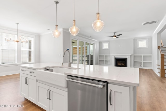 3836 Mason Port Dr, Wilmington, NC 28409 - kitchen with stainless steel dishwasher, open floor plan, a center island with sink, light wood finished floors, and ornamental molding