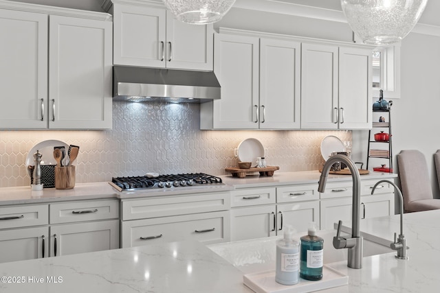 kitchen with pendant lighting, extractor fan, stainless steel gas cooktop, white cabinets, and decorative backsplash