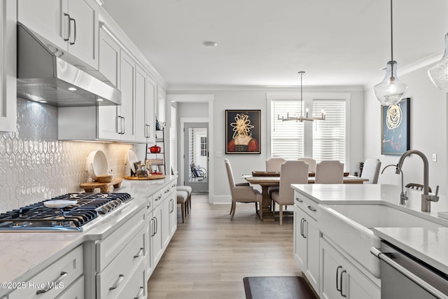 kitchen featuring pendant lighting, stainless steel appliances, light stone counters, white cabinets, and decorative backsplash