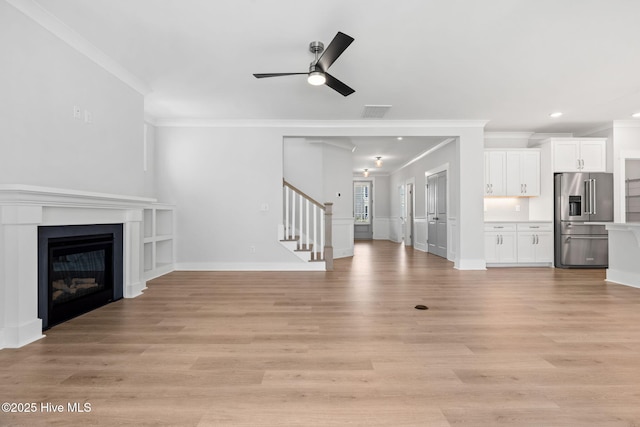 3836 Mason Port Dr, Wilmington, NC 28409 - unfurnished living room with ornamental molding, ceiling fan, stairway, light wood-style floors, and a glass covered fireplace