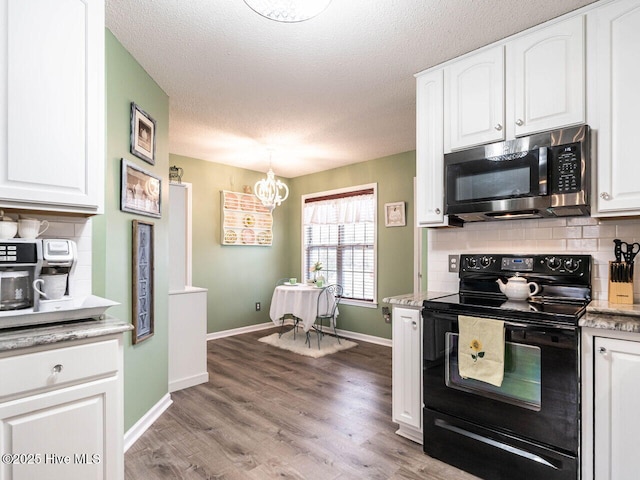 kitchen featuring pendant lighting, white cabinets, backsplash, black range with electric cooktop, and light wood-type flooring