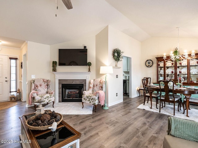 living room with an inviting chandelier, hardwood / wood-style flooring, and vaulted ceiling