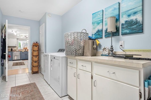 clothes washing area featuring light tile patterned flooring, cabinets, and washer and dryer