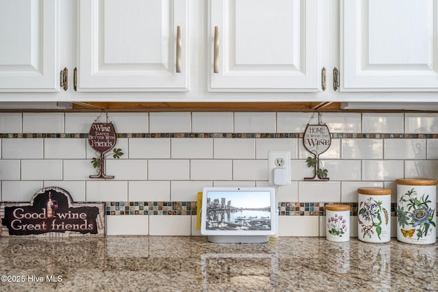 room details featuring white cabinetry, backsplash, and light stone countertops