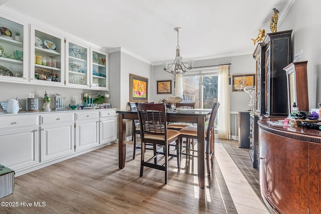 dining room featuring an inviting chandelier, light hardwood / wood-style flooring, and ornamental molding