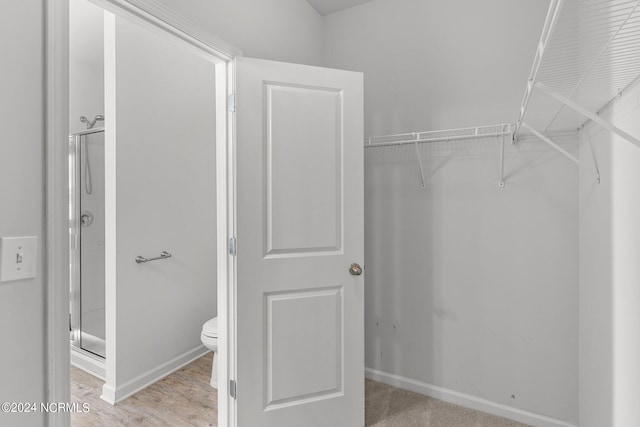 interior space featuring wood-type flooring, an enclosed shower, and toilet