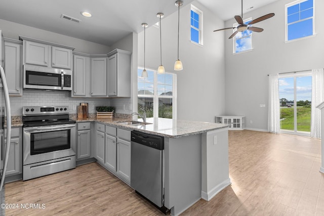 kitchen featuring sink, stainless steel appliances, decorative backsplash, stone countertops, and decorative light fixtures