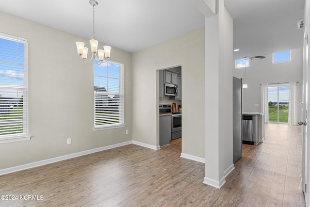 unfurnished dining area with a chandelier and light wood-type flooring