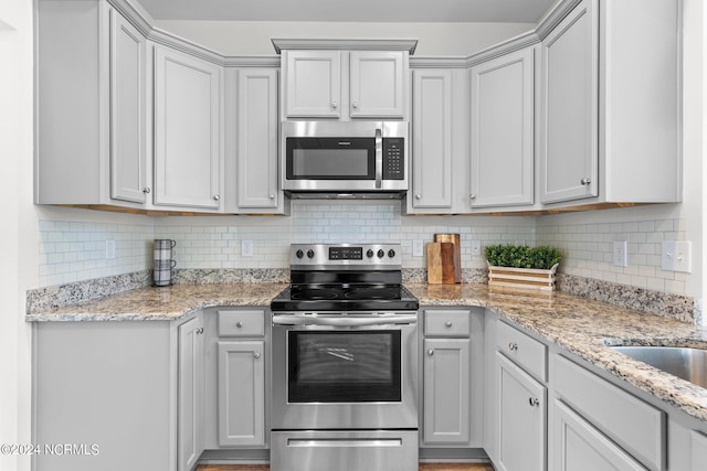 kitchen featuring tasteful backsplash, stainless steel appliances, and light stone counters