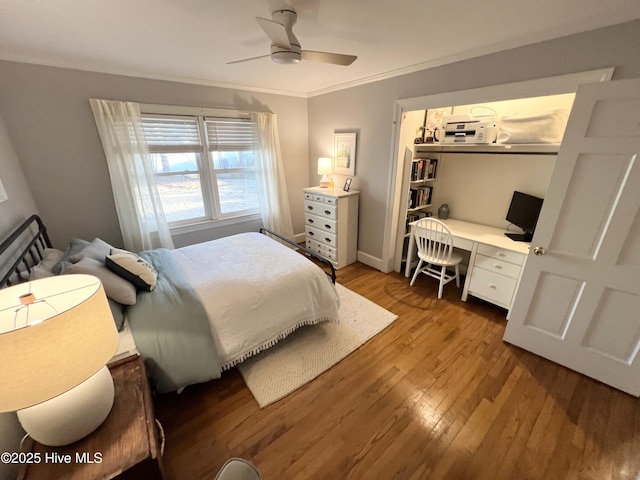 bedroom featuring hardwood / wood-style flooring, built in desk, ornamental molding, and ceiling fan