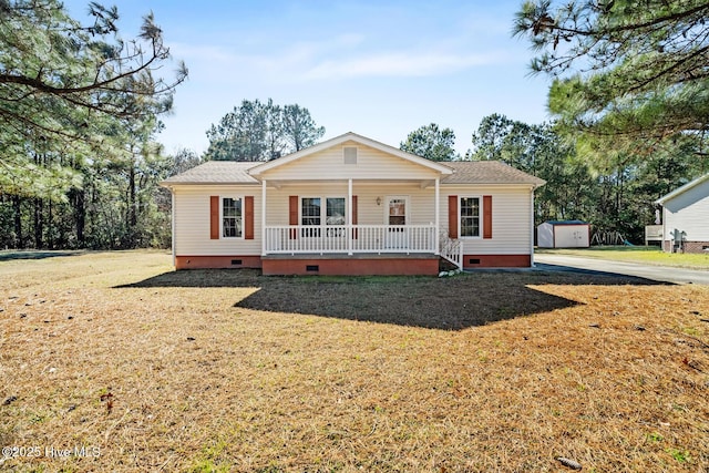 single story home featuring covered porch, a storage unit, and a front yard