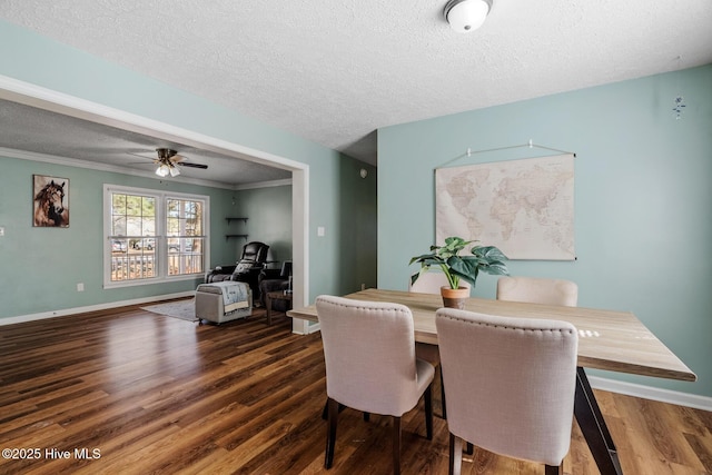 dining space with a textured ceiling, dark wood-type flooring, and ornamental molding