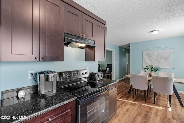 kitchen with dark stone countertops, light hardwood / wood-style floors, a textured ceiling, and electric range