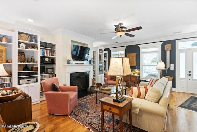 living room with crown molding, ceiling fan, and light hardwood / wood-style floors