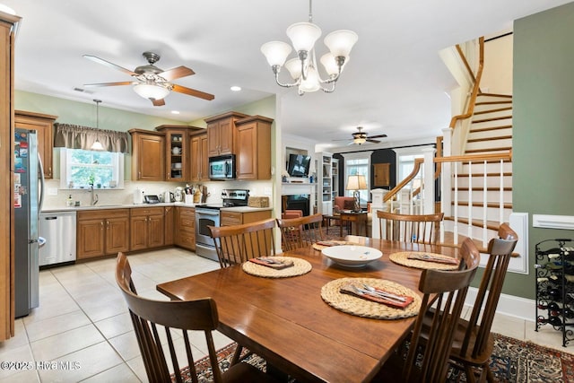 tiled dining space featuring sink, ornamental molding, and ceiling fan