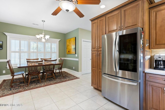 kitchen with light tile patterned flooring, hanging light fixtures, stainless steel fridge, ceiling fan with notable chandelier, and decorative backsplash