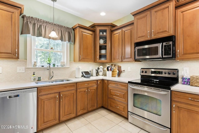 kitchen with decorative light fixtures, sink, backsplash, light tile patterned floors, and stainless steel appliances