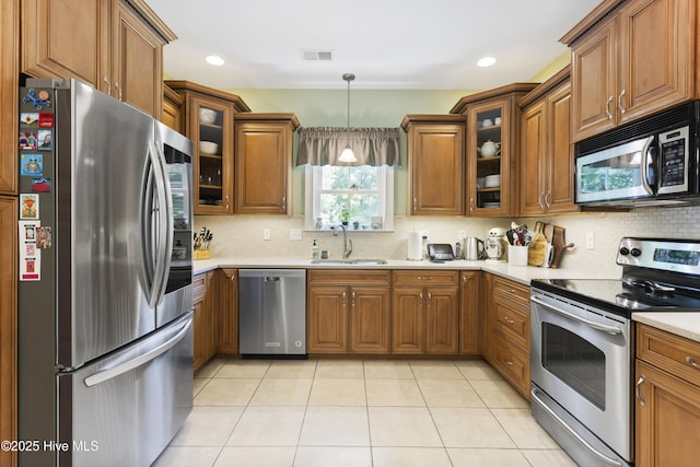 kitchen with sink, light tile patterned floors, appliances with stainless steel finishes, tasteful backsplash, and decorative light fixtures