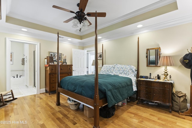 bedroom with crown molding, light hardwood / wood-style flooring, and a raised ceiling