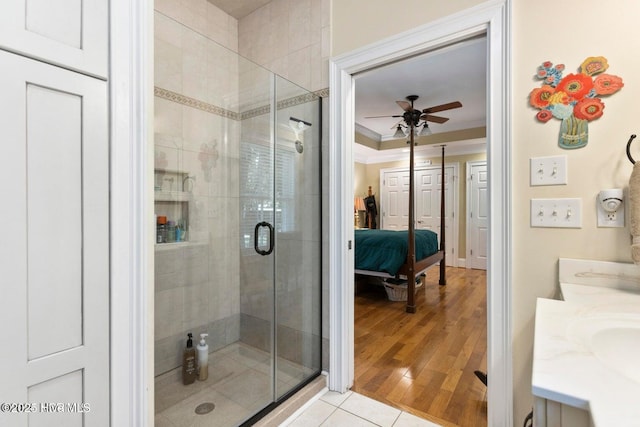 bathroom with tile patterned floors, a shower with shower door, crown molding, vanity, and ceiling fan