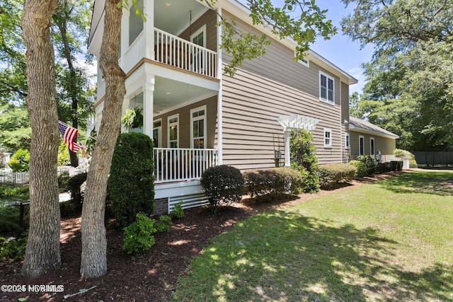 view of side of home with a lawn and a balcony