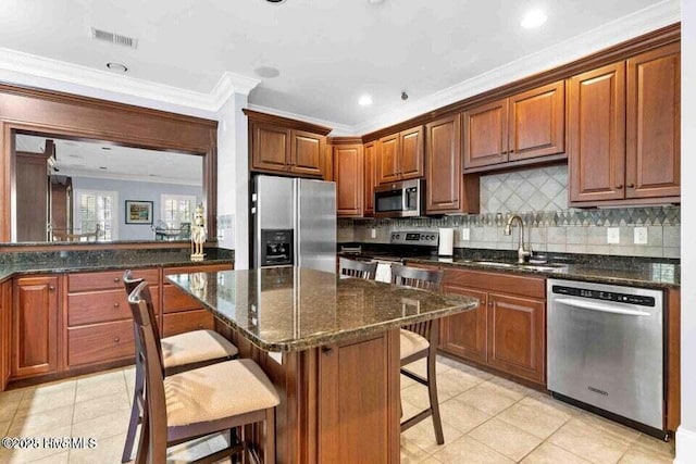 kitchen with sink, dark stone countertops, a breakfast bar area, decorative backsplash, and stainless steel appliances