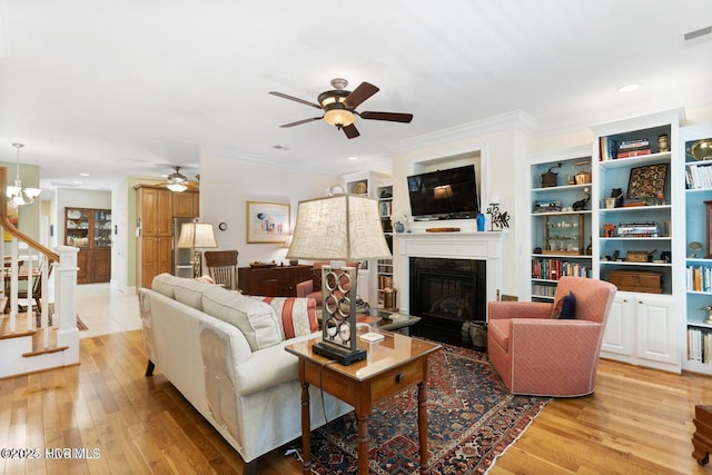 living room with ornamental molding, ceiling fan with notable chandelier, and light hardwood / wood-style flooring