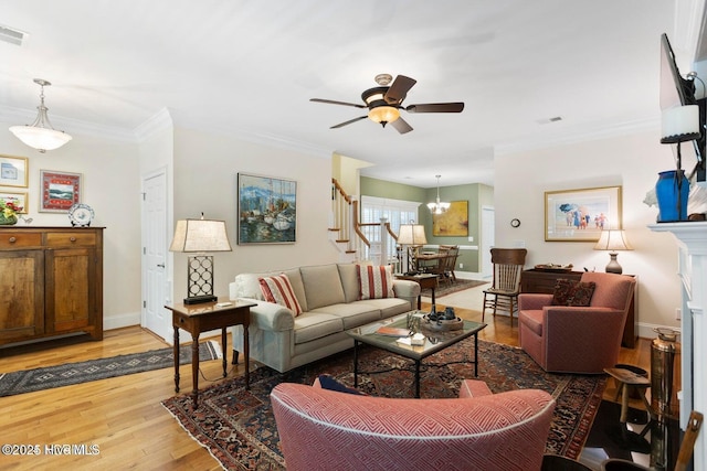 living room featuring hardwood / wood-style flooring, ornamental molding, and ceiling fan with notable chandelier