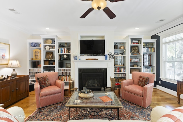 living room featuring crown molding, ceiling fan, and light hardwood / wood-style flooring