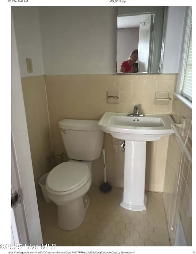 bathroom with tile walls and toilet