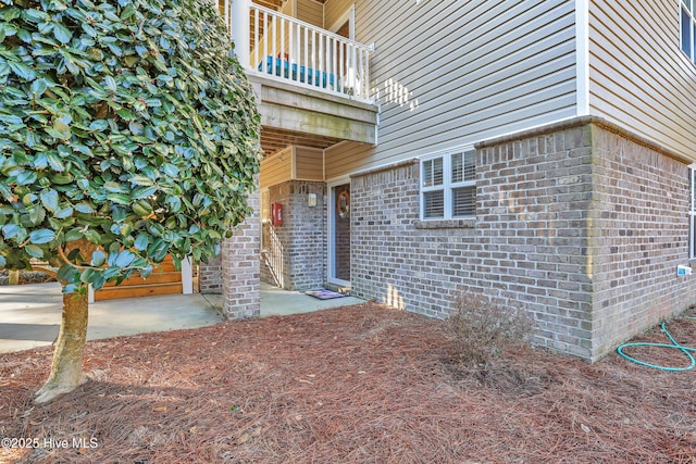 view of exterior entry with a balcony and a patio area